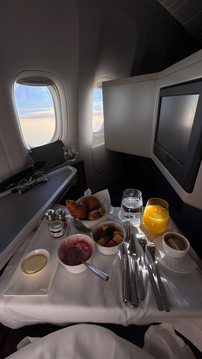services-02 Luxurious first class breakfast setup with croissants and juice on a plane.